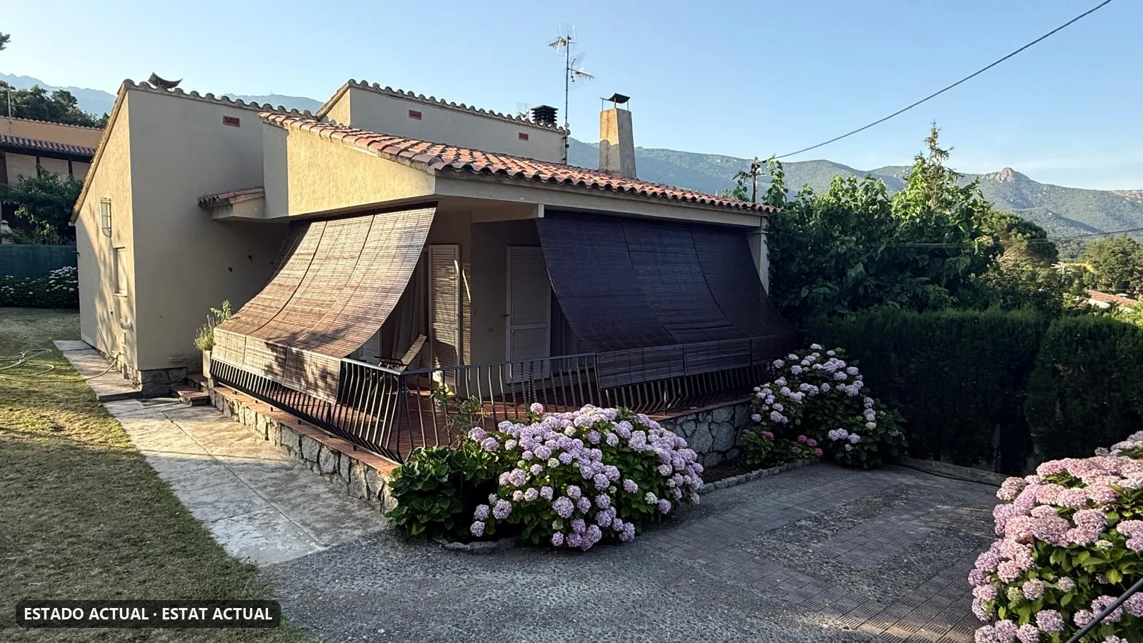 Foto real del pas lateral d'una casa abans de l'obra: terra i gespa al costat de la façana